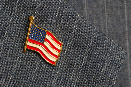 An American flag lapel pin on a pinstripe suit lapel